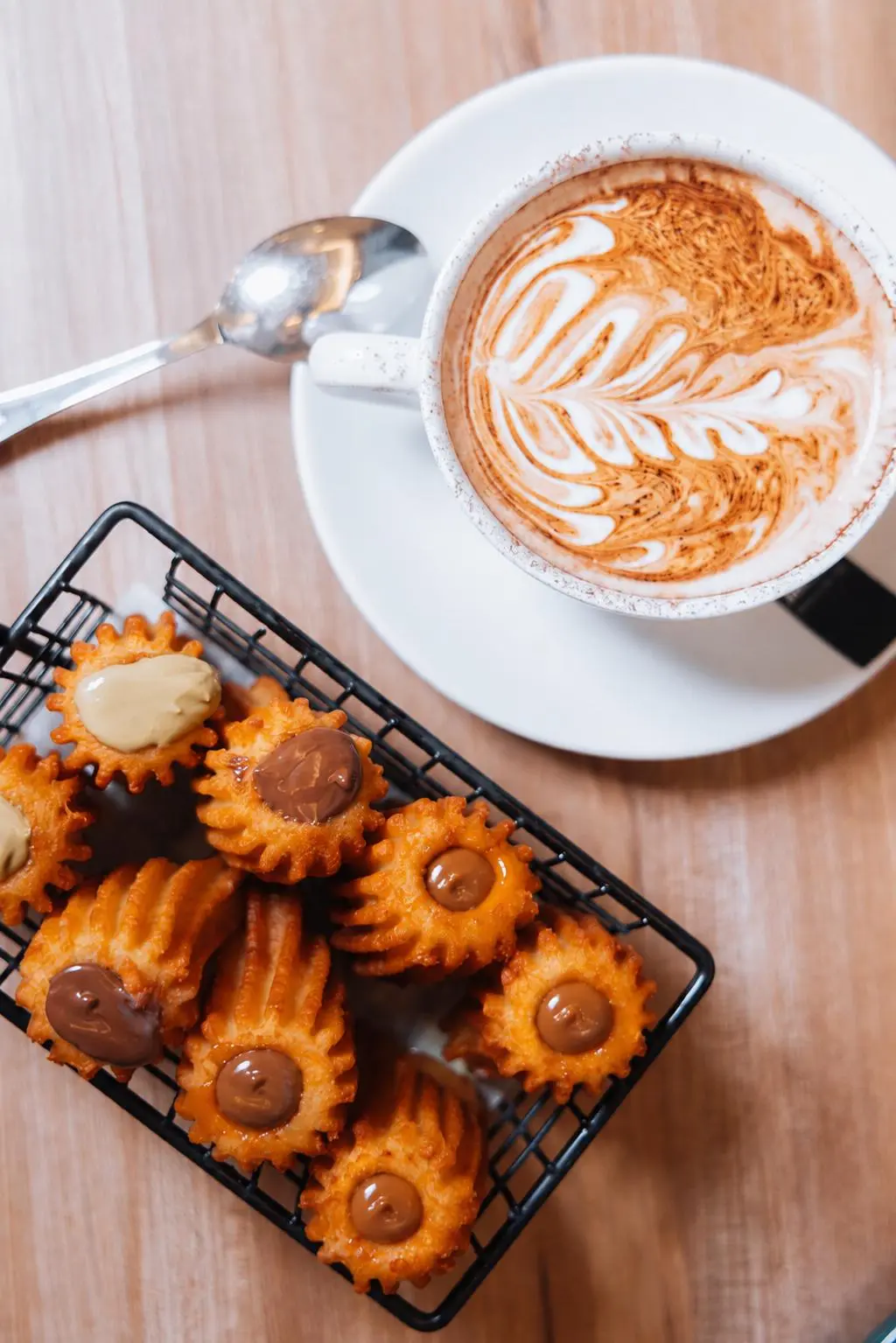 Café con arte latte junto a una cesta de porras rellenas de crema