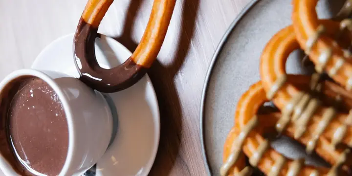 Churro recién hecho mojado en una taza de chocolate caliente