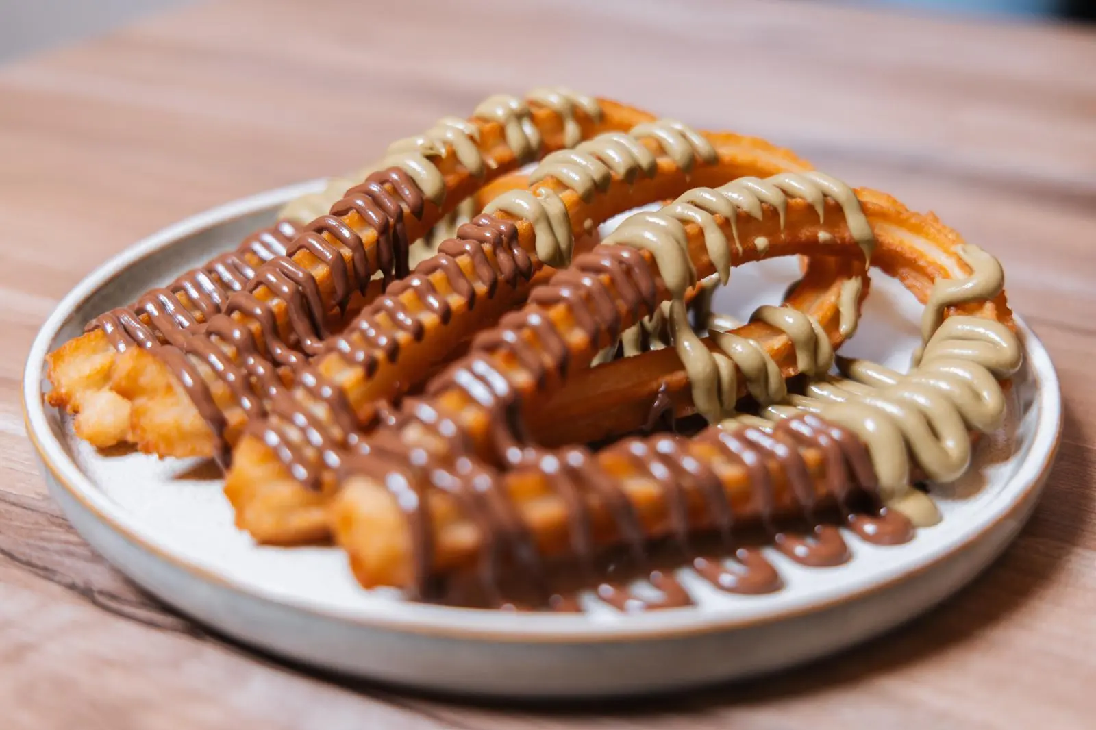 Churros loop con crema de pistacho y chocolate servidos en plato de cerámica