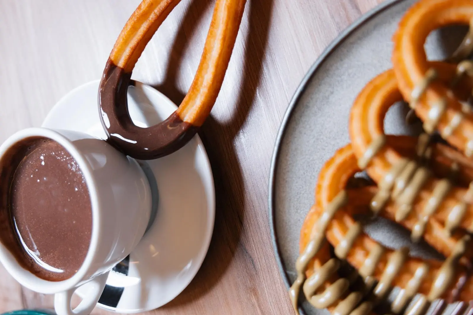 Detalle de churros con chocolate y crema de pistacho sobre plato artesanal