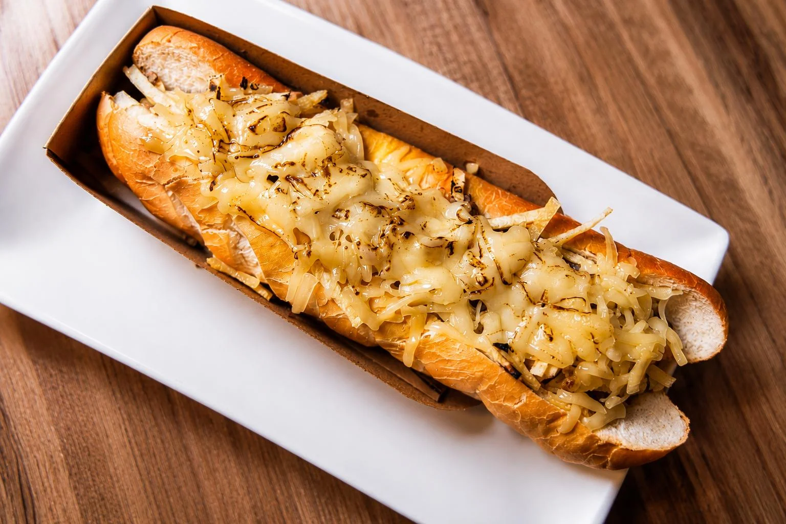 Hot dog especial gratinado con queso fundido y cebolla a la plancha