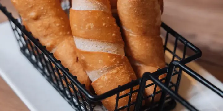 Tequeños dorados en una cesta con salsa para mojar